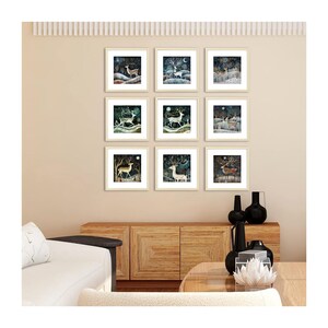 May include: Nine framed prints of a whimsical forest scene with deer, trees, and a moon. The prints are arranged in a grid pattern on a beige wall.
