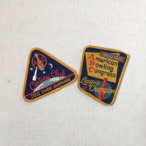 May include: Two vintage bowling patches. One is a blue triangle with "Century Club" and "100 Over Average" text. The other is a square patch with "American Bowling Congress League Champion" text and "1960-1961" text.