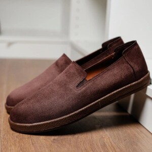 Puede incluir: Un par de zapatos sin cordones de ante marr&oacute;n. Los zapatos tienen una puntera redondeada y un perfil bajo, con una suela marr&oacute;n oscuro. La parte superior es de un material de ante suave y texturizado en un rico color marr&oacute;n. Los zapatos est&aacute;n dise&ntilde;ados para uso casual.