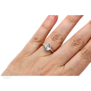 K&ouml;nnte beinhalten: Ein Ring aus Ros&eacute;gold mit einem runden Aquamarin. Der Ring ist mit kleinen Diamanten auf der Ringschiene besetzt.