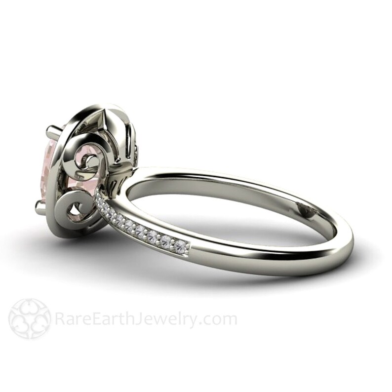 May include: A delicate engagement ring with a pale pink gemstone set in a filigree design. The band is accented with a row of small diamonds.