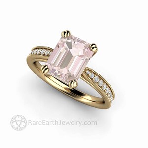 May include: A gold engagement ring with a pink morganite center stone and a diamond band. The ring has a vintage style with a delicate milgrain detail.
