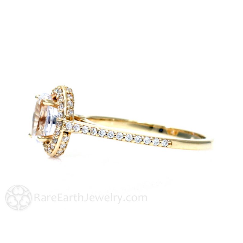 May include: A gold engagement ring with a large oval-shaped center stone surrounded by a halo of smaller diamonds. The band is also set with smaller diamonds.