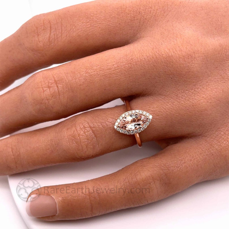 Marquise cut Morganite ring with diamond halo. Morganite marquise halo ring in rose gold with diamonds, morganite ring on the hand photo.