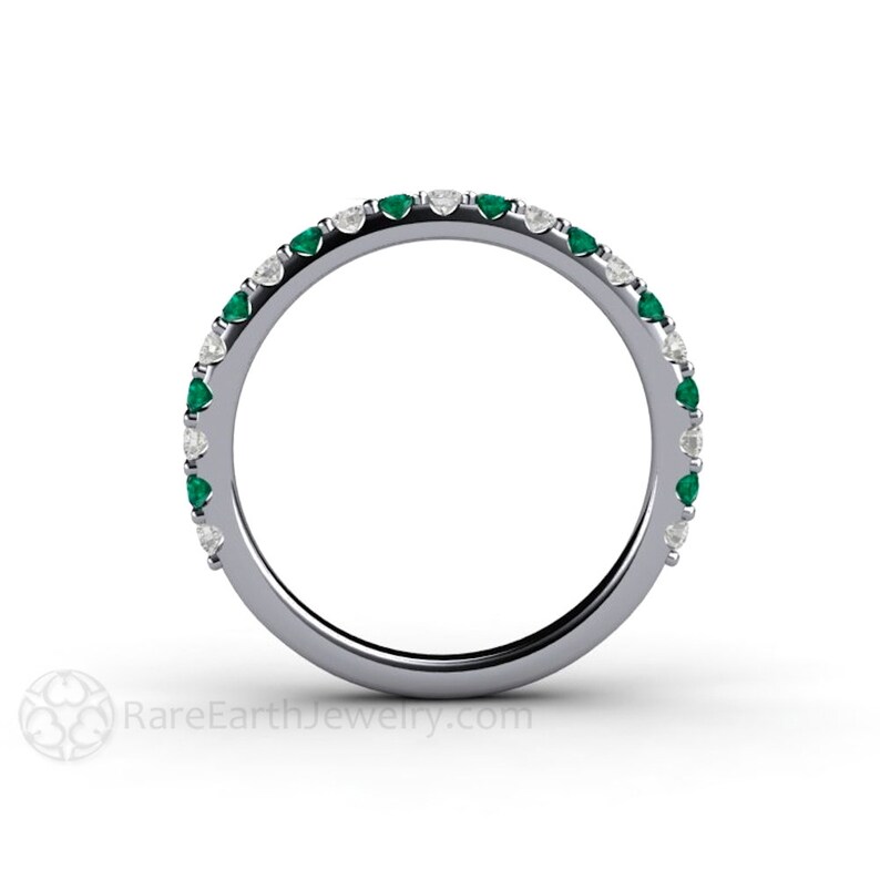 K&ouml;nnte beinhalten: Ein silberner Bandring mit abwechselnd Smaragden und Diamanten. Der Ring hat eine durchgehende Reihe kleiner, rund geschliffener Smaragde und Diamanten, die um das Band gesetzt sind. Die Edelsteine sind gleichm&auml;&szlig;ig verteilt und erzeugen ein funkelndes und elegantes Design.