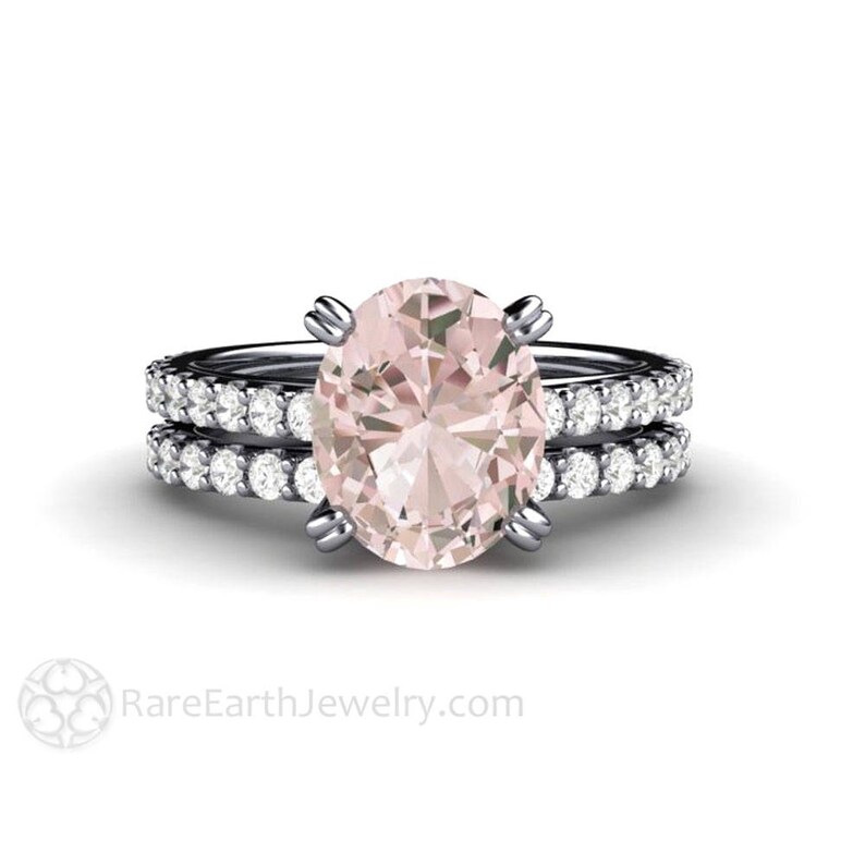 Op de afbeelding: Een delicate verlovingsring met een grote ovale roze morganiet-edelsteen omgeven door een halo van kleinere diamanten. De ring is gezet op een dunne band met een bijpassende band bezet met diamanten.