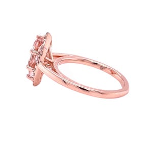 May include: A rose gold ring with a pink gemstone set in a halo of smaller stones.