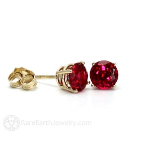 May include: A pair of gold stud earrings with round red ruby gemstones.