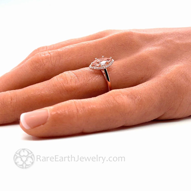 May include: A rose gold engagement ring with a pear-shaped center stone and a halo of smaller diamonds.