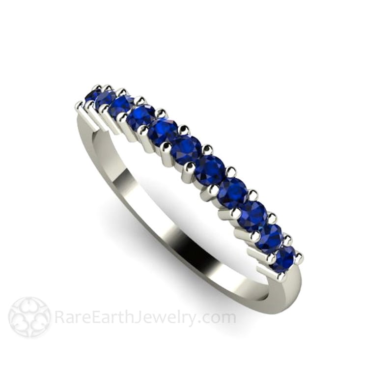 May include: A silver band ring with a row of blue sapphires. RareEarthJewelry.com