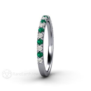 K&ouml;nnte beinhalten: Ein silberner Ring mit abwechselnd Smaragden und Diamanten. Der Ring hat ein Band aus kleinen, rund geschliffenen gr&uuml;nen Smaragden und klaren Diamanten, die eng aneinander gesetzt sind. Der Ring wird vor wei&szlig;em Hintergrund gezeigt.