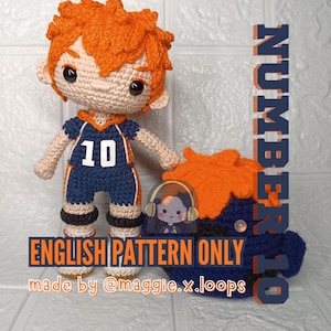 May include: A crocheted doll with bright orange hair and a dark blue sports uniform featuring the number 10 in white. Beside it sits a matching dark blue crocheted accessory with orange hair. Text reads: NUMBER 10, ENGLISH PATTERN ONLY, @maggie.x.loops.