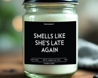 May include: A black and white candle jar with the text "Smells like she's late again". The candle is made with 100% vegan soy wax and is non-toxic. It is 9 ounces and made in the USA.
