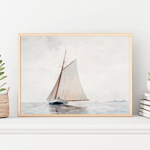 Puede incluir: Una pintura al agua enmarcada de un velero con velas blancas en un mar azul claro. El velero navega lejos del espectador, con la proa del barco mirando hacia el lado izquierdo de la imagen. El cielo es de color gris claro con algunas nubes.