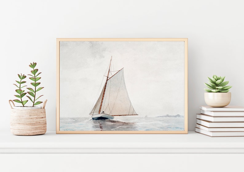 Puede incluir: Una pintura al agua enmarcada de un velero con velas blancas en un mar azul claro. El velero navega lejos del espectador, con la proa del barco mirando hacia el lado izquierdo de la imagen. El cielo es de color gris claro con algunas nubes.