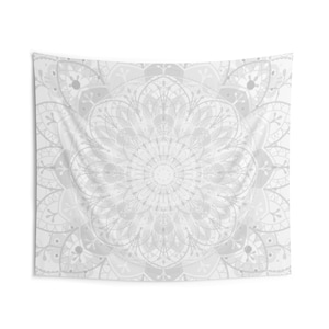 May include: White tapestry with a large, intricate mandala design in the center. The mandala is made up of overlapping circles and swirls, creating a complex and beautiful pattern.