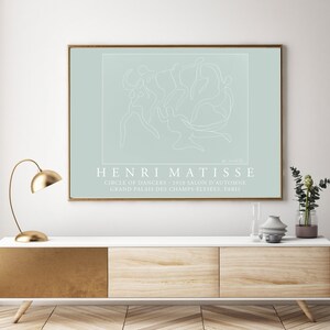 May include: A light blue poster with a white line drawing of dancers in a circle. The text "HENRI MATISSE" is below the drawing, followed by "CIRCLE OF DANCERS - 1910 SALON D'AUTOMNE GRAND PALAIS DES CHAMPS-ELYS&Eacute;ES, PARIS".