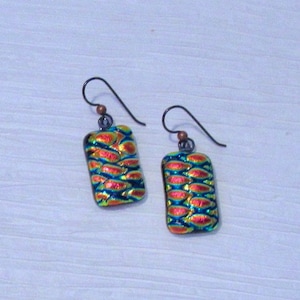 May include: A pair of earrings with a rectangular iridescent glass design. The glass is a mix of blue, green, and orange colors. The earrings are made with silver hooks.