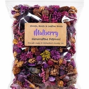 May include: A clear plastic bag filled with dried botanical potpourri in shades of purple, magenta, and brown. A tan label reads: Shoots, Roots & Leather Boots, Mulberry, Handcrafted Potpourri, Proudly Made in Robertson County, TN.