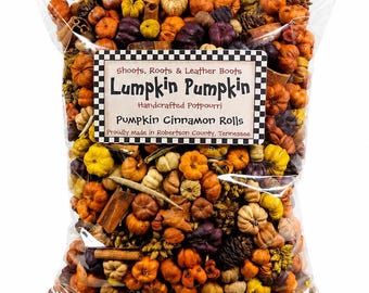 May include: A clear plastic bag filled with potpourri containing small orange, yellow, and purple pumpkins, pinecones, and cinnamon sticks. The label reads: Shoots, Roots & Leather Boots, Lumpkin Pumpkin, Handcrafted Potpourri, Pumpkin Cinnamon Rolls, Proudly Made in Robertson County, Tennessee.