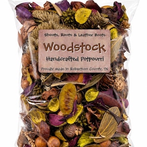 May include: A clear plastic bag filled with dried potpourri containing purple, yellow, and brown botanical elements. A rectangular label reads: Shoots, Roots & Leather Boots, Woodstock, Handcrafted Potpourri, Proudly Made in Robertson County, TN.