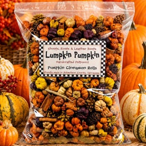 May include: A clear plastic bag filled with decorative potpourri containing small orange, yellow, and purple pumpkins, cinnamon sticks, and pinecones. A white label with a black and white checkered border reads: Shoots, Roots & Leather Boots, Lumpkin Pumpkin, Handcrafted Potpourri, Pumpkin Cinnamon Rolls, Proudly Made in Robertson County, Tennessee.