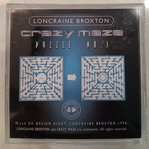 Könnte beinhalten: Eine schwarze und blaue Spielbox mit dem Titel "crazy maze" und dem Text "Puzzle No. 3". Die Box zeigt ein Labyrinth-Puzzle mit blauem Hintergrund und einem weißen Labyrinth-Muster. Das Spiel ist von Loncraine Broxton und hat ein Copyright von 1998.