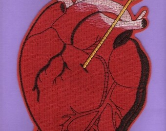 Puede incluir: Un corazón rojo bordado con una flecha dorada que lo atraviesa. El corazón tiene venas detalladas y un contorno negro.