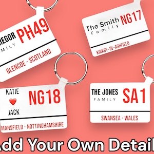 May include: Four white rectangular keychains with black borders and red text. Each keychain features a family name, a location, and a postcode. The keychains are on a pink background.