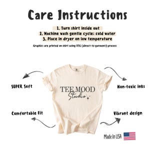 May include: A beige t-shirt with the text "TEE MOOD Studio" printed in black. The shirt is made with non-toxic inks and has a comfortable fit. Care instructions are listed above the shirt.