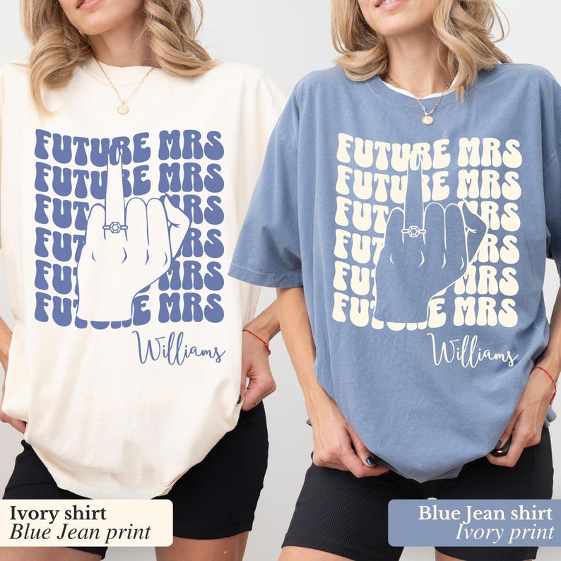 May include: Two t-shirts, one ivory and one blue jean, with a graphic print of a hand with a ring on the finger and the text "FUTURE MRS" repeated in a retro font. The text "Williams" is printed below the graphic on both shirts.