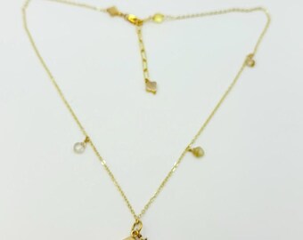 May include: A delicate gold-colored necklace with a small, yellow gemstone pendant. The necklace features a fine chain with several small, dangling charms and a star charm. The pendant is approximately 0.5 inches in length.