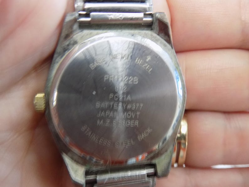 Pu&ograve; includere: Il retro di un orologio argentato con un cinturino in acciaio inossidabile. Il quadrante dell'orologio ha il testo "BASE MEMA BEZEL PR228 2 PC21A BATTERY #377 JAPAN MOVT M.ZEROER STAINLESS STEEL BACK".