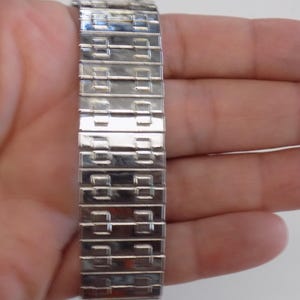 Pu&ograve; includere: Un braccialetto per orologio argentato con un motivo geometrico unico. Il braccialetto &egrave; realizzato con maglie metalliche che sono collegate tra loro per formare un cinturino flessibile e resistente.