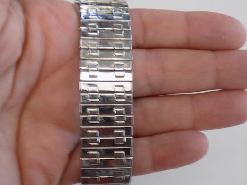 Pu&ograve; includere: Un braccialetto per orologio argentato con un motivo geometrico unico. Il braccialetto &egrave; realizzato con maglie metalliche che sono collegate tra loro per formare un cinturino flessibile e resistente.