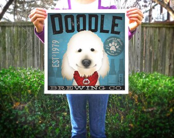 May include: Square print featuring a white dog with a red bandana, the text "DOODLE BREWING CO." and "EST. 1979". The background is a light blue with beer bottles. The print is held up by a person.