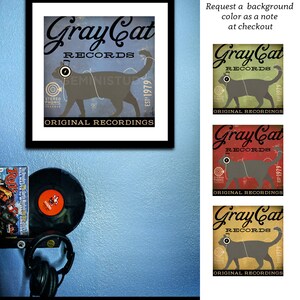 May include: A vintage-style illustration of a gray cat wearing headphones with the text "Gray Cat Records" and "Est. 1979" in a blue, red, or yellow background. The text "Original Recordings" is below the cat.