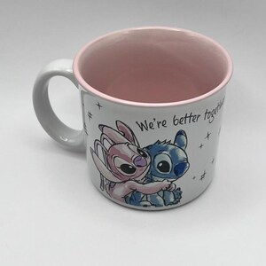 May include: White ceramic mug with a pink interior and handle. The mug features a cartoon illustration of two characters hugging, with the text "We're better together" and star accents.
