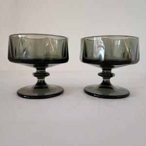 Könnte beinhalten: Zwei klare, dunkelgraue Glasschalen für Desserts mit geriffeltem Rand und einem kurzen Stiel.