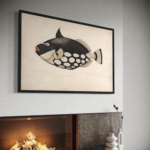 May include: A framed art print depicting a detailed illustration of a black and white fish with large white spots. The fish has a distinctive dorsal fin. The artwork is displayed above a fireplace, adding a decorative element to the room.