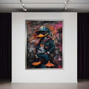 May include: A colorful, abstract painting of a duck wearing a baseball cap, sunglasses, and a denim jacket. The duck is standing on a street with graffiti in the background. The painting is framed in a silver frame.