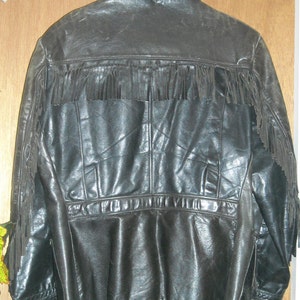Pode incluir: Uma jaqueta de couro preta com detalhes de franjas nos ombros e na bainha inferior. A jaqueta tem um fecho de correr e v&aacute;rios bolsos.