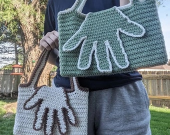 May include: Two crocheted hand-shaped bags. The larger bag is green with white trim and the smaller bag is beige with brown trim.