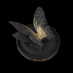 May include: A black decorative box with a butterfly design. The butterfly has black wings with gold accents and a gold body. The box has the words "Just for you" in gold script.