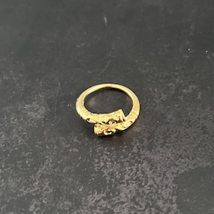 May include: A gold ring with a unique, intricate design. The ring features a twisted band with a detailed, textured pattern.