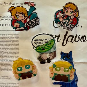 May include: Four colourful, cartoon-style stickers featuring characters from the video game "The Legend of Zelda: Breath of the Wild". The stickers are printed on clear plastic and have a glossy finish. The characters are Link, Zelda, and a cat.