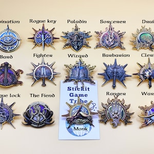 以下が含まれることがあります： 「Divination」、「Rogue key」、「Paladin」など、ファンタジーのクラス名がそれぞれデザインされた、詳細な金属製ピンのコレクション。ピンは金と銀の配色で、複雑なディテールが施されています。