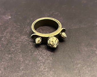 Könnte beinhalten: Ein goldfarbener Ring mit drei dekorativen Dornen. Die Dornen sind in Form von kleinen, spitzen Blättern geformt.