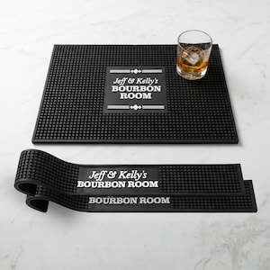May include: Black rubber bar mats with a textured surface. The mats feature the text "Jeff & Kelly's BOURBON ROOM" in white. A rocks glass with ice and amber liquid sits on one mat. Ideal for a home bar.