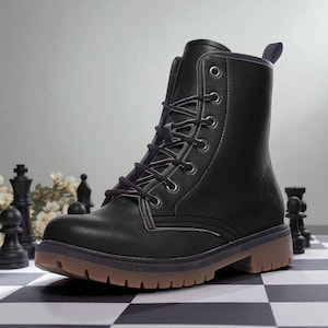 May include: Black combat boot with a brown sole and a lace-up design. The boot has a rounded toe and a sturdy, textured sole. The boot is set on a black and white checkered surface.